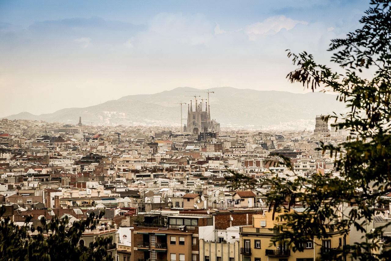 Blick über die Dächer von Barcelona auf die Sagrada Família, dahinter Berge